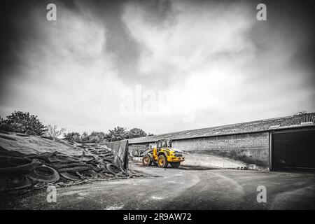 Excavatrice jaune sur un site de construction dans le temps nuageux spectaculaire Banque D'Images