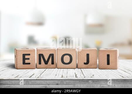 L'emoji mot sur un panneau en bois dans une salle lumineuse sur un bureau blanc Banque D'Images