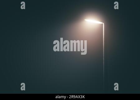 Lampadaire avec lumière vive dans un brouillard brumeux la soirée d'une humeur dramatique Banque D'Images