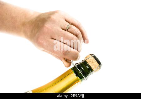 La main féminine l'ouverture d'une bouteille de champagne un réveillon Banque D'Images