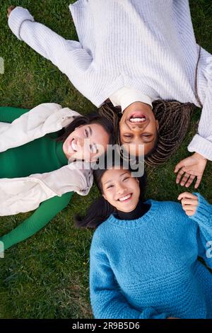 Portrait joyeux de trois meilleurs amis allongé sur l'herbe ayant le bon temps de rire et de regarder l'appareil photo Banque D'Images