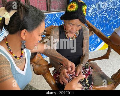 Buscalan, Philippines. 24th mai 2023. Maria Oggay (r), populairement connue sous le nom d'Apo Whang-OD, le plus ancien mamabatok ou tatoueur traditionnel aux Philippines, montre son pouce droit à sa petite-nièce Grace Palicas. À 106 ans, Whang-OD pratique encore l'art antique du batok - la technique de tatouage à la main en utilisant une épine de citron et de la suie de charbon qu'elle a appris comme une adolescente. (À dpa 'Tattoo art à 106 ans: Une visite avec Vogue Cover Girl Whang-OD') Credit: Girlie Linao/dpa/Alay Live News Banque D'Images