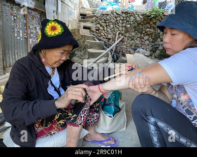 Buscalan, Philippines. 24th mai 2023. Maria Oggay, connue sous le nom d'Apo Whang-OD, le plus vieux mambabatok ou tatoueur traditionnel aux Philippines, tatouages visiteur Tina Rose Gado utilisant des techniques traditionnelles. À 106 ans, Whang-OD pratique encore l'art antique du batok - la technique de tatouage à la main en utilisant une épine de citron et de la suie de charbon qu'elle a appris comme une adolescente. (À dpa 'Tattoo art à 106 ans: Visite de Vogue Cover Girl Whang-OD') Credit: Girlie Linao/dpa/Alay Live News Banque D'Images