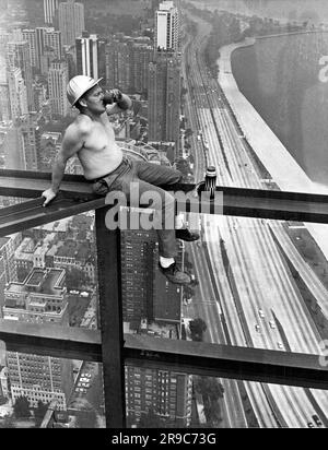 Chicago, Illinois : 1965. Un ouvrier de l'acier sur une poutre prend une pause-café au-dessus de Lakeshore Drive à Chicago. Banque D'Images