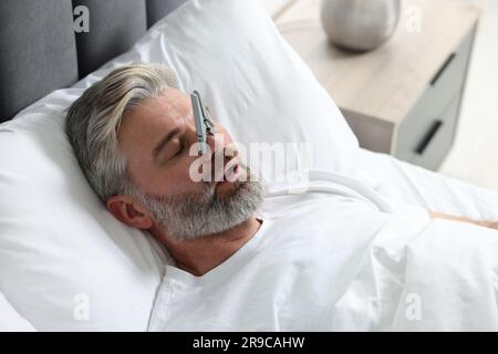 Homme dormant avec des épingles à linge sur son nez dans le lit à la maison. Problème de ronflement Banque D'Images