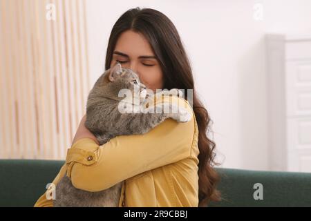 Jeune femme embrassant son adorable chat à la maison, espace pour le texte Banque D'Images