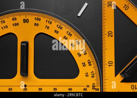 Rapporteur, règle triangulaire et craie sur table noire, plat Banque D'Images