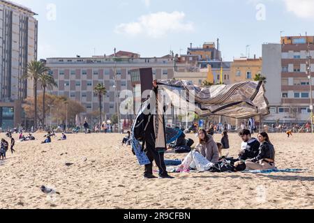 Barcelone, Espagne - 10 FÉVRIER 2022 : vendeurs illégaux de vêtements de plage sur la plage de Barceloneta. Banque D'Images