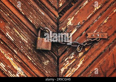 Ancien cadenas rouillé corrodé avec chaîne sur la porte de la ferme en bois comme arrière-plan Banque D'Images