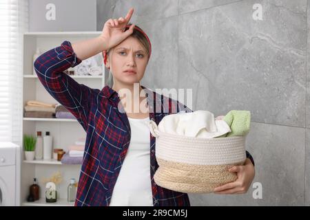 Femme fatiguée avec panier de linge dans la salle de bains Banque D'Images