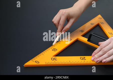 Femme dessin avec craie et règle triangulaire sur tableau noir, gros plan. Espace pour le texte Banque D'Images