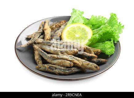 Assiette avec de délicieuses anchois frits, des feuilles de citron et de laitue sur fond blanc Banque D'Images