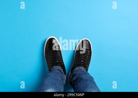 Homme dans des sneakers élégantes sur fond bleu clair, vue du dessus Banque D'Images