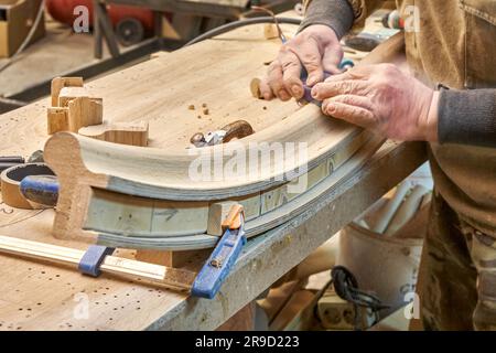 Charpentier sable cintrage garde-corps en bois avec papier de verre en atelier de clôture. Maître senior fait le détail de l'escalier en colimaçon pour l'intérieur de la maison Banque D'Images