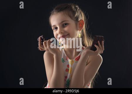 Chocolat et joli petit portrait de femme affamé. Belle fille prête à manger barre de chocolat. Banque D'Images