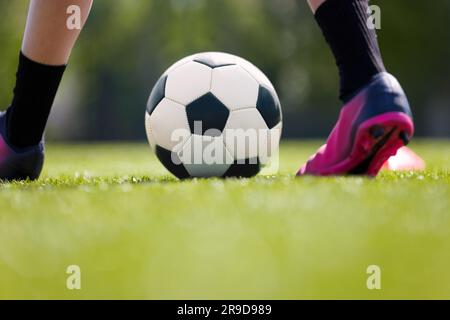 Football pour les jeunes. Jeune garçon portant des crampons et des chaussettes de football. Ballon de football joueur Kicking Classic Banque D'Images