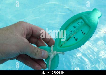 un homme vérifie la température à l'aide d'un thermomètre par temps ensoleillé. Banque D'Images