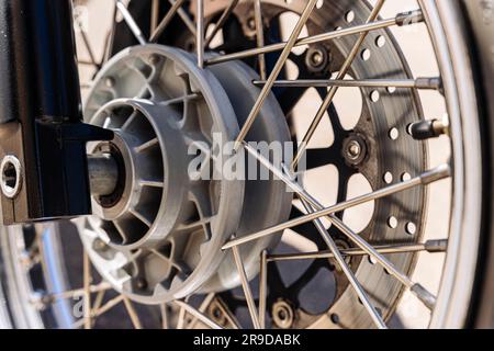 la roue avant de la moto. les rayons de la roue et du pneu ainsi que la jante chromée brillante de la roue et le disque de frein perforé sont visibl Banque D'Images