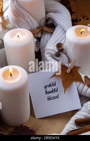 Reconnaissance reconnaissant texte béni message carte de voeux concept célébrer Thanksgiving vacances d'automne dans une maison confortable sur le seuil de la fenêtre Hygge atmosphère esthétique l'automne laisse des épices et des bougies sur pull blanc tricoté dans des lumières jaunes chaudes. Encore la vie. Pluie à l'extérieur Banque D'Images