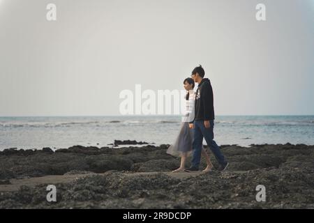 Un jeune couple gai debout sur le rivage d'une plage Banque D'Images