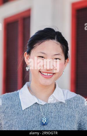 Portrait individuel vertical en gros plan d'une jeune femme chinoise heureuse, souriante et regardant l'appareil photo. Une fille d'école de teengage regardant devant avec l'expression amicale et les dents blanches. Joyeuse femme. Photo de haute qualité Banque D'Images