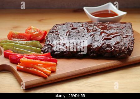 Côtes de porc grillées savoureuses avec légumes grillés sur une planche à découper Banque D'Images