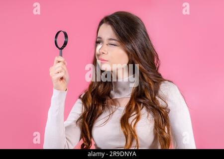 Business brunette avec une loupe devant ses yeux sur fond rose Banque D'Images