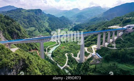 Guiyang, province chinoise de Guizhou. 26th juin 2023. Un train d'essai passe un grand pont dans le comté de Guiding, dans la province de Guizhou, au sud-ouest de la Chine, à 26 juin 2023. Avec le départ du train d'essai 55311 de la gare de Guiyang Nord, le chemin de fer à grande vitesse de Guiyang-Nanning a officiellement commencé ses essais de fonctionnement lundi. Le chemin de fer, à une vitesse prévue de 350 kilomètres à l'heure, relie Guiyang de la province de Guizhou et Nanning de la région autonome de Guangxi Zhuang. Credit: Long Jianrui/Xinhua/Alamy Live News Banque D'Images