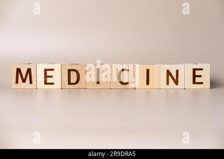 Le mot MÉDECINE sur des cubes en bois sur un fond beige neutre studio. Copier l'espace. Écrit. Les mots de texte ont leur importance. Suppléments pour la santé humaine. Essentia Banque D'Images