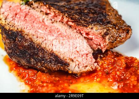 Un gros plan d'un plat fraîchement préparé avec des morceaux de viande en foyer, entouré d'autres ingrédients qui composent le repas. Banque D'Images