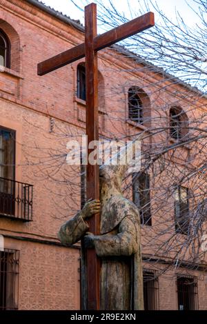 Ségovie, Espagne - 18 février 2022: Statue de l'homme tenant une grande croix, portant une robe traditionnelle de cérémonie avec chapeau pointu et masque. Banque D'Images