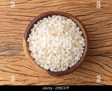 Canjica séché, maïs hominy ou blanc sur un bol sur une table en bois. Banque D'Images