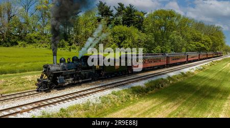 Une vue aérienne du côté d'une locomotive à vapeur antique et d'un autocar de passager s'est arrêtée et a soufflé de la fumée et de la vapeur, en attendant les passagers Banque D'Images