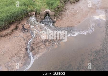 Vue aérienne du premier lait (à gauche) et du tuyau d'eau gallois qui se déverse dans l'estuaire de Cleddau. Le méplat intertidal est décoloré en rouge en raison du dépôt Banque D'Images
