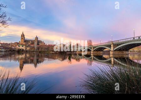 Salamanque, Espagne - 20 février 2022 : vue panoramique de Salamanque avec la cathédrale et le pont Enrique Estevan sur la rivière Tormes à la belle lumière du coucher du soleil. Banque D'Images