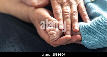 La vieille femme tient les jambes de l'enfant dans ses mains. Banque D'Images