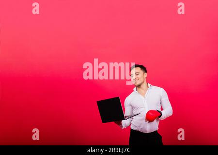 Guy dans des gants de boxe et des vêtements de formalwear ordinateur de punch isolé sur rouge, cyber-intimidation. Banque D'Images