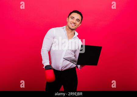 Guy dans des gants de boxe et des vêtements de formalwear ordinateur de punch isolé sur rouge, cyber-intimidation. Banque D'Images