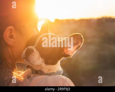 Le chiot mignon repose sur l'épaule d'une femme. Journée claire et ensoleillée. Gros plan, extérieur. Lumière du jour. Concept de soins, d'éducation, de formation à l'obéissance et d'élevage d'animaux de compagnie Banque D'Images