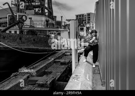 Une jeune fille prend une cigarette sournoise s'allume derrière un conteneur le secteur du port de Wellington New Zealand Capital City. Photo : Rob Watkins Banque D'Images