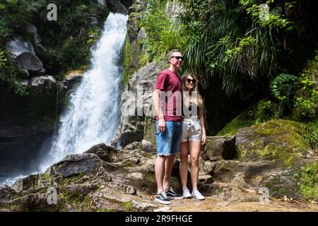 Un couple pose aux cascades de Wainui Falls Wainui Bay, région de Tasman, Nouvelle-Zélande, Île du Sud, Parc national d'Abel Tasman. Photo : Rob Watkins Banque D'Images