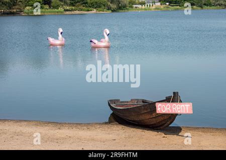 Jouets de piscine rose gonflables et bateau à rames en bois de location à la baie de Töölönlahti à Helsinki, Finlande Banque D'Images