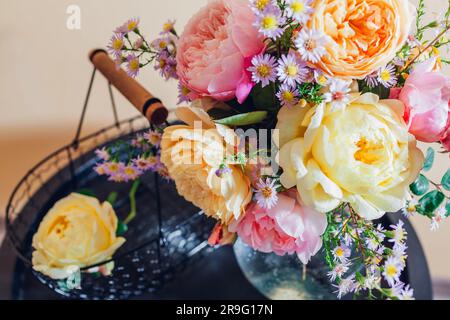 Bouquet frais de fleurs roses mis dans un vase en verre sur la table. Gros plan des fleurs jaunes roses avec panier. Décoration intérieure Banque D'Images