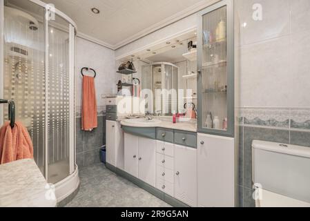 toilettes traditionnelles avec une armoire en bois blanc et vert avec un évier en porcelaine encastré dans un comptoir en marbre sous un miroir intégré et un quart de ci Banque D'Images