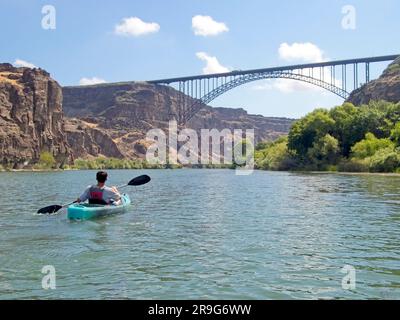 Un adolescent pagaie un kayak vers le pont Perrine lors d'une belle journée sur la rivière Snake à Twin Falls, Idaho. Banque D'Images