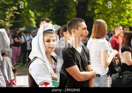 Photo d'une fille debout, , portant une tenue serbe traditionnelle dans la ville d'Erdevik, Serbie à côté d'un jeune homme avec une marque de rouge à lèvres sur le salut Banque D'Images