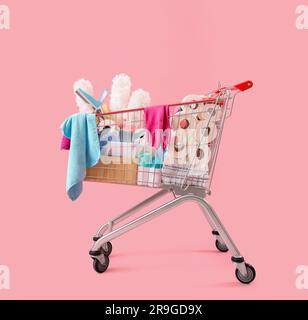 Chariot plein de produits de nettoyage sur fond rose Banque D'Images