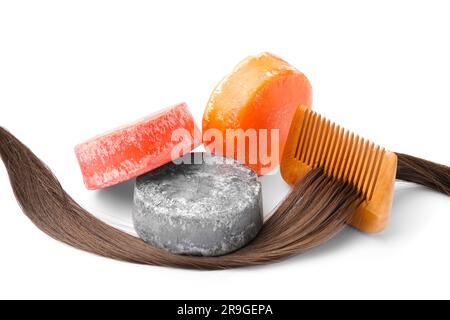 Barres de shampooing unies colorées avec cheveux et peigne sur fond blanc Banque D'Images