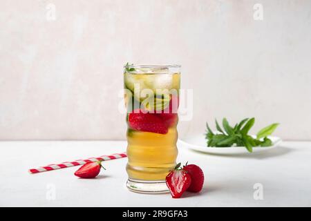 Verre de thé glacé avec fraise et menthe sur fond blanc Banque D'Images