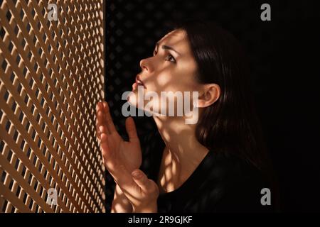 Femme priant à Dieu pendant la confession en cabine Banque D'Images